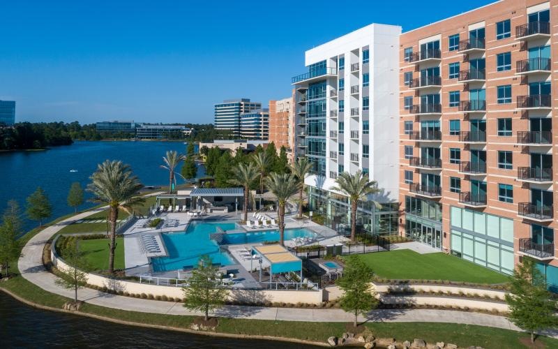 a building with trees and grass by a body of water