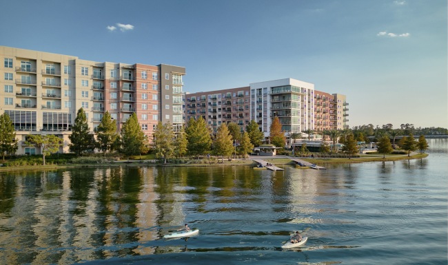 people with kayaks on a body of water in front of large buildings
