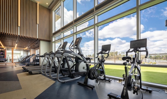 a gym with exercise equipment and large windows