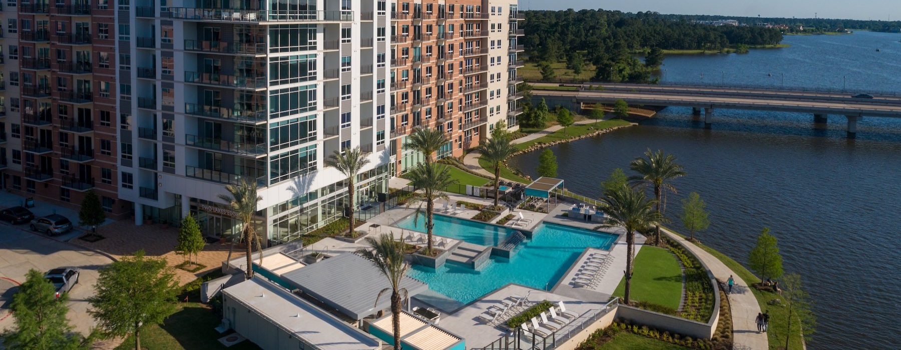 a building with a pool in front and larger body of water surrounding it all