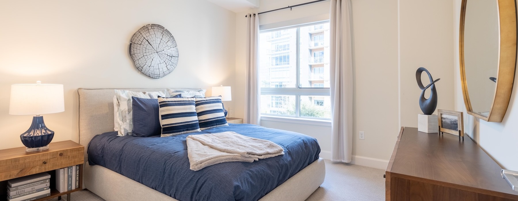 bedroom with bed lamps mirror dresser and windows